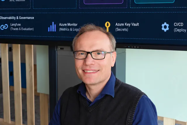 Paweł Pisarski at a desk in front of a screen showing an enterprise RAG architecture